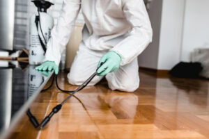 Exterminator In coveralls performing pest control services with a Sprayer.